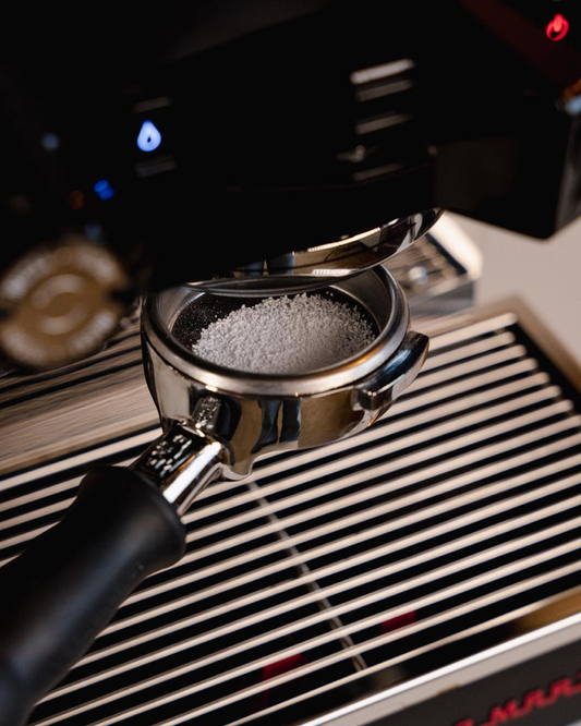 Blind basket filled with espresso machine cleaning powder before backflushing a commercial espresso machine.
